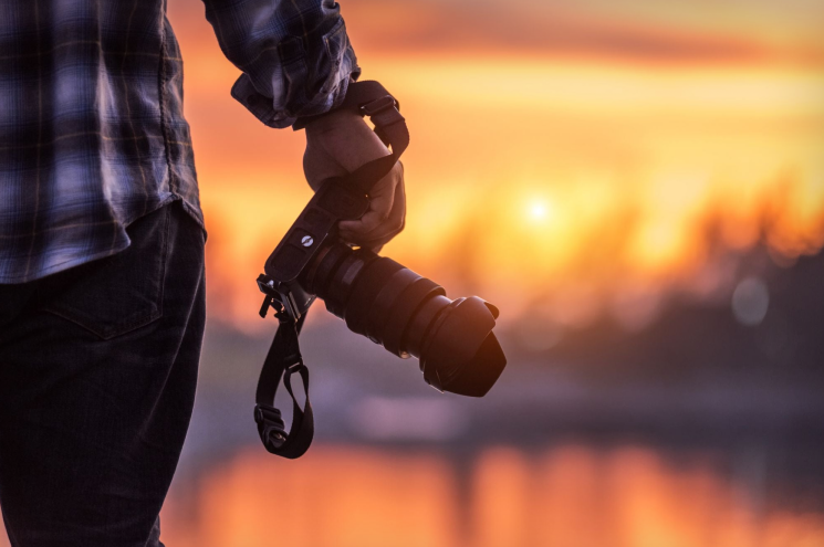 Photographer holding a camera during sunset